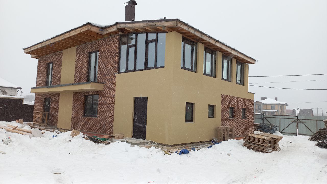 Загородный дом с фасадом из светлой штукатурки и клинкерной плитки зимой